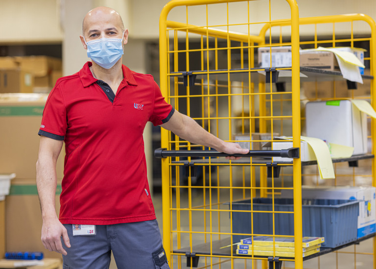 Magazijnier trekt een kar vooruit met materiaal